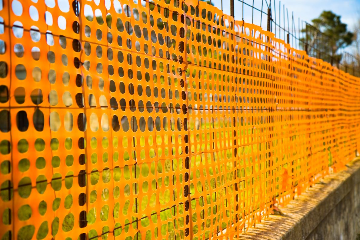 An orange temporary fence set up against wooden poles.