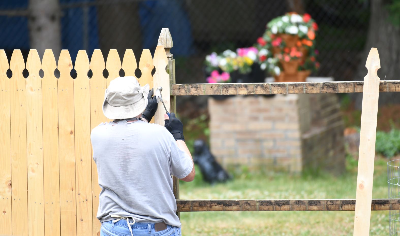 A man hammers a wooden fence post into place.